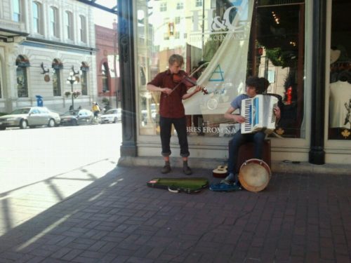 Fiddle player and accordian player perform for money on the street