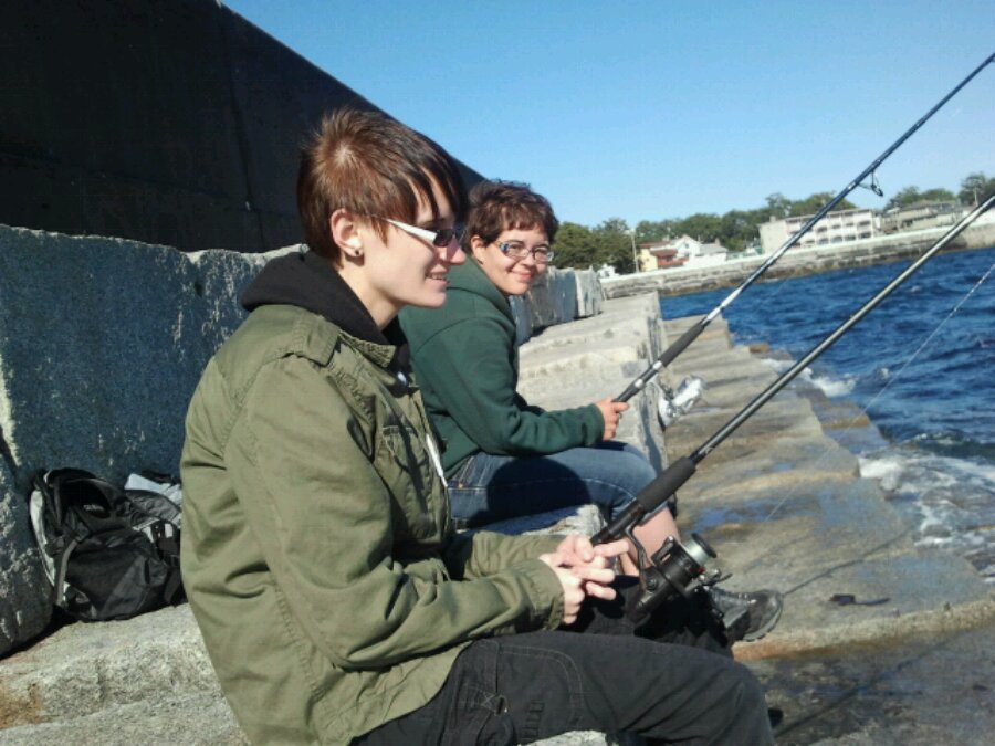 Two cool people sit on the Victoria breakwater fishing in the sunshine