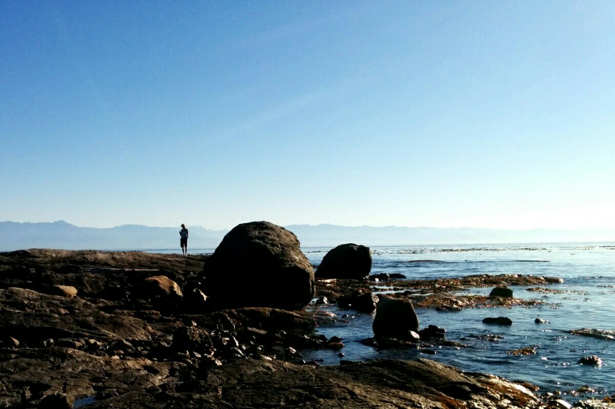 Human stands in shadow on Clover Point in the Salish Sea