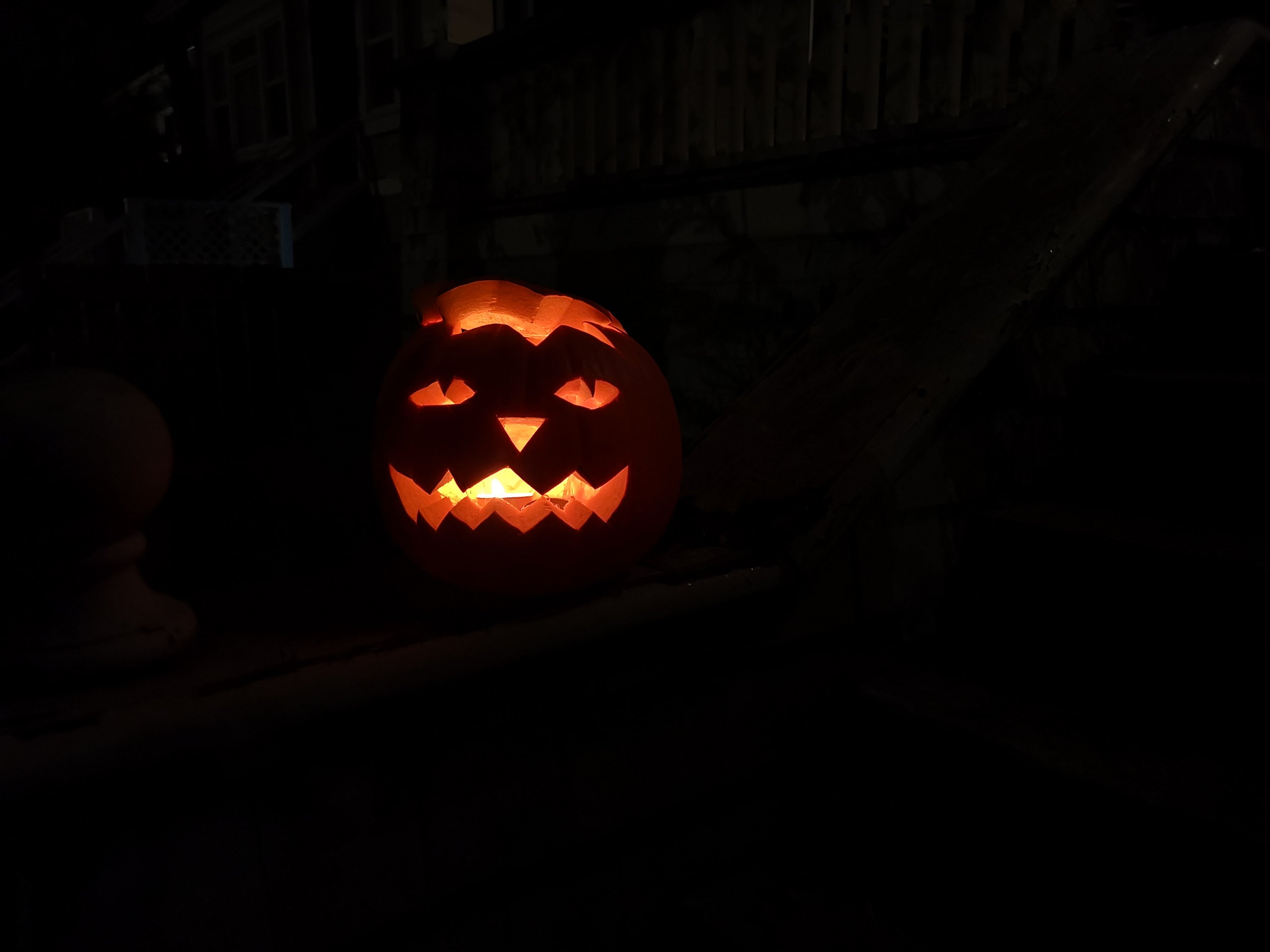 A glowing pumpkin on the banner of our front step, in VicWest.
