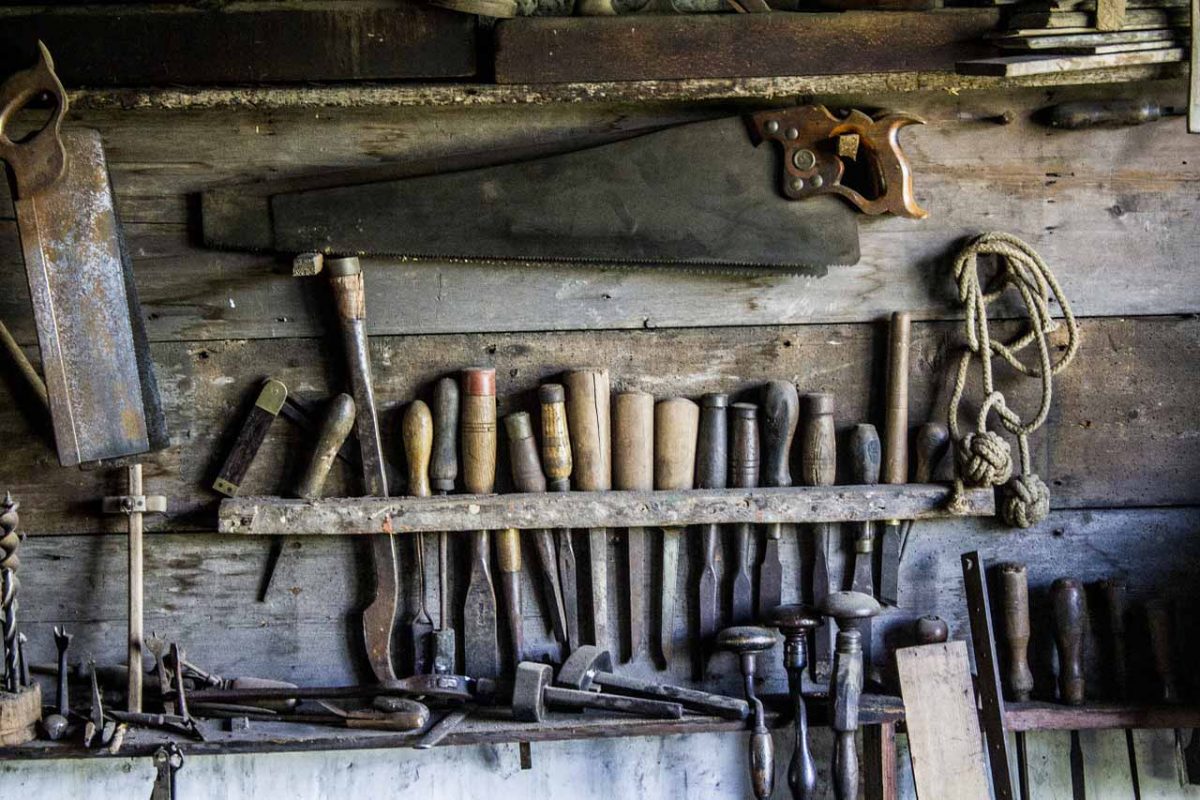 Some old, but sound, tools at the workbench, including chisels, saws, knives and drills.