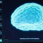 A brain scan lights up bright blue on a computer screen along side of a bunch of graphs and charts.