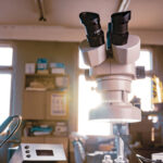 A microscope sits on a desktop of a busy lab.
